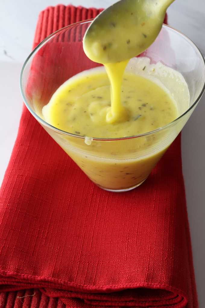 creamy hollandaise sauce with tarragon dripping from a spoon