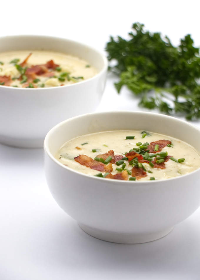 two bowls of low carb clam chowder with parsley in the background