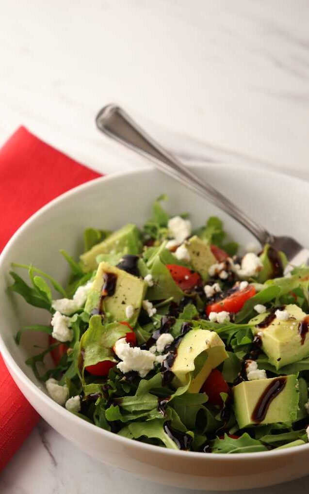 Arugula salad with feta cheese and balsamic glaze in a bowl